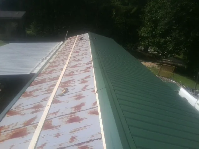 Old rusted panels beside newly installed green metal roofing — Wind Damage Roof Repair by Roofing Brothers in Salem